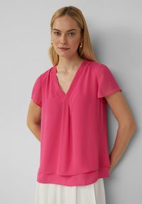 Fuchsia Kurzarmoberteil mit V-Ausschnitt, das Falten an der Brust und einen geschichteten Saum aufweist. Hergestellt aus leichtem, glattem Stoff.