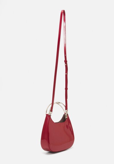 Red patent leather handbag with a sleek, curved shape and adjustable strap. Features silver-tone hardware and open top with interior lining.