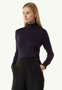 Granatowy sweter w golf w dopasowanym kroju z długimi rękawami, wykonany z miękkiej dzianiny, w połączeniu z czarnymi spodniami o wysokim stanie.