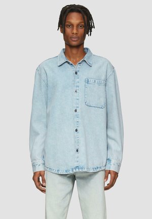 Lichtblauwe denim shirt met lange mouwen, knoopsluiting aan de voorkant en borstzak. Het heeft een relaxte pasvorm en een licht gescheurde zoom.