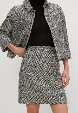 Chaqueta texturizada en blanco y negro con cuello, cierre de botones y mangas tres cuartos, combinada con una falda lápiz a juego.