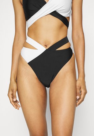 Biquíni preto e branco com design entrelaçado, recortes nas laterais e tecido de textura suave. O estilo de cintura alta realça a forma.