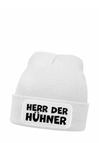 White knit beanie featuring a folded cuff. Centered rectangular label with black text: "HERR DER HÜHNER." Text includes a stylized font.