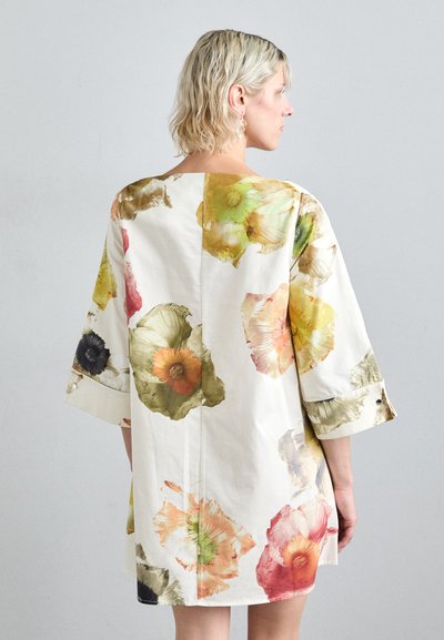 Vestido de algodón floral con mangas de 3/4, presenta patrones de flores vibrantes en amarillo, naranja, rosa, verde y negro sobre un fondo crema.