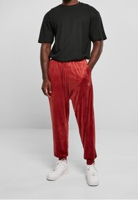 Svart kortärmad t-shirt kombinerad med röda velourbyxor. Byxorna har resårmidja och uppvikta fållar, och kompletteras med vita sneakers.