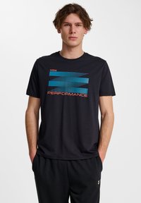 Zwart kortemouwt-shirt met blauwe en rode "PERFORMANCE" graphic op de voorkant. Gemaakt van zachte stof met een ronde hals en een relaxte pasvorm.
