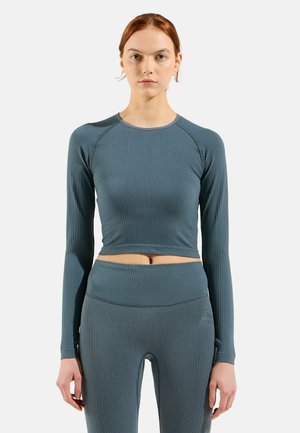 Langärmliges, cropped Oberteil aus geripptem Stoff in Tealfarbe, mit Rundhalsausschnitt und eingesetzten Ärmeln, kombiniert mit passenden, hochtaillierten Leggings.