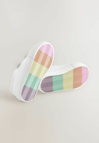 Vita sneakers med en strukturerad yta. Sulorna har ett pastellfärgat zigzag-mönster i lila, rosa, grönt och gult.