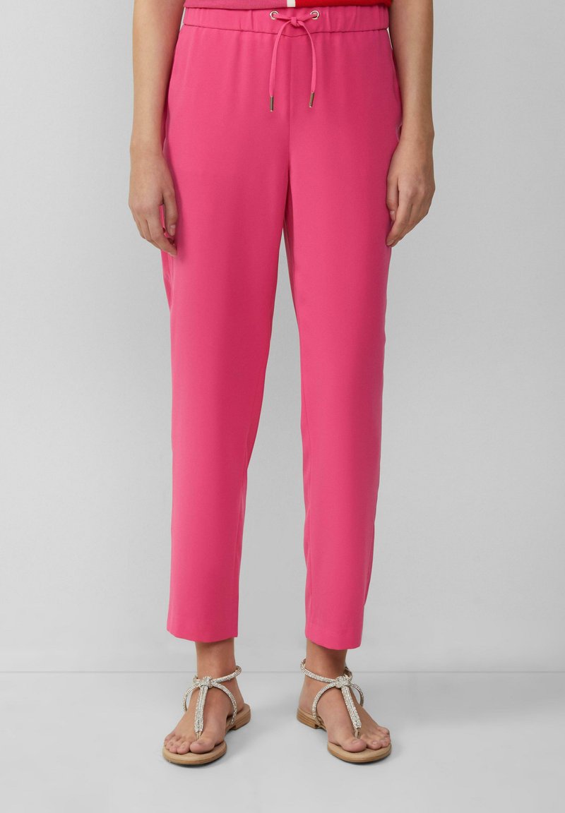 Roze, lichtgewicht pantalons met een tailleband met trekkoord en taps toelopende benen, gecombineerd met platte, versierde sandalen. Soepele textuur, casual ontwerp.