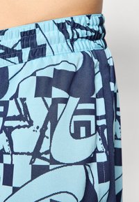 Shorts featuring a blue and navy geometric pattern, elastic waistband, breathable fabric, and a smooth texture.