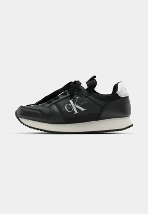 Czarne skórzane sneakersy z białą podeszwą, z logo po boku, czarnymi sznurowadłami i kontrastującym wzmocnieniem na pięcie. Klasyczny design sportowy.