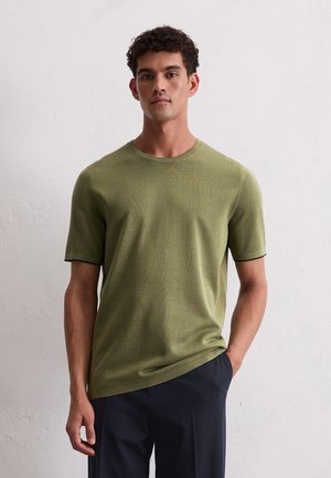 Olijfgroene t-shirt met korte mouwen en ronde hals, gemaakt van textuurstof, met contrasterende zwarte accenten aan de mouwranden.