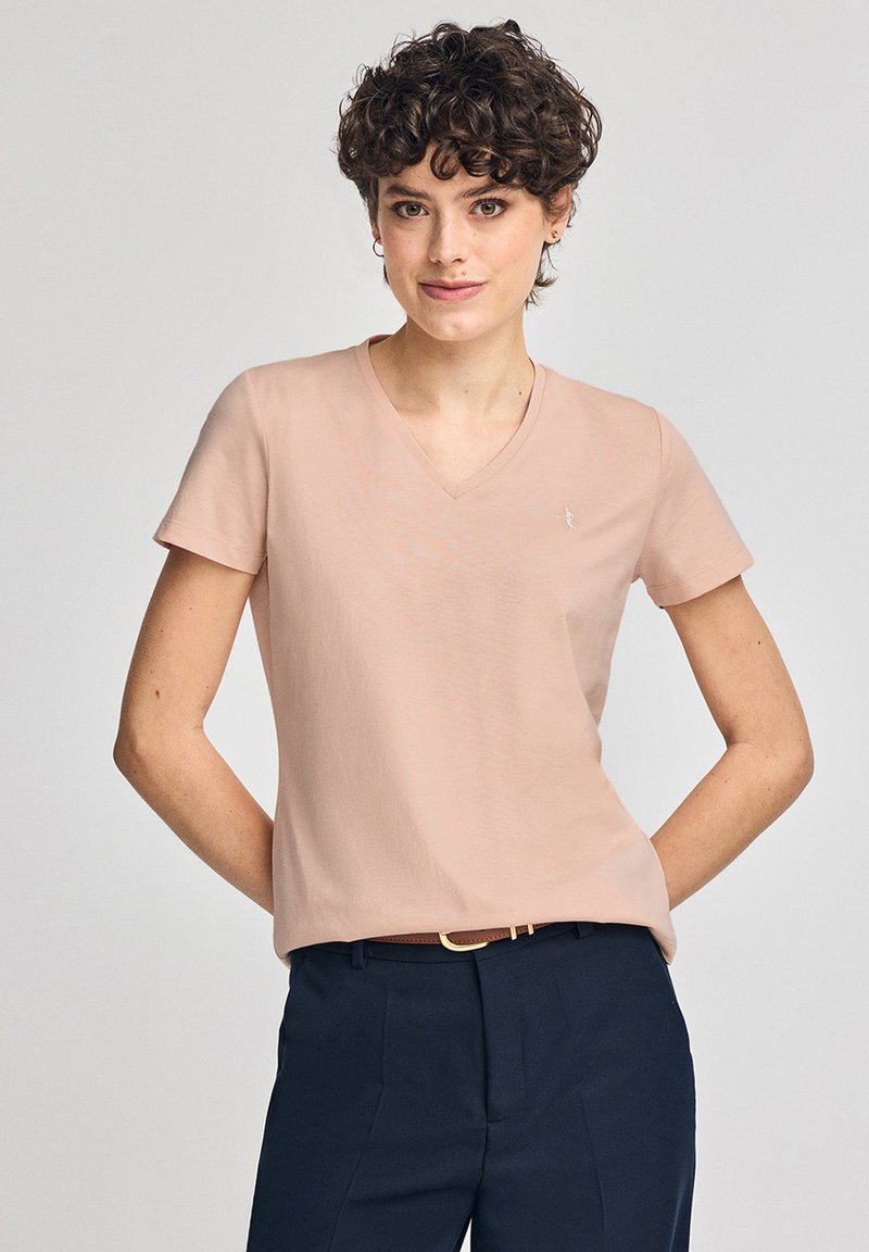 V-ringad, kortärmad t-shirt i mjukt rosa tyg. Har en liten broderad logotyp på den övre vänstra bröstet. Matchas med mörka byxor.