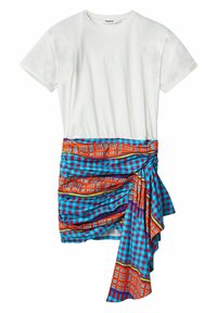 Valkoinen puuvillapaita lyhyillä hihoilla, yhdistettynä värikkääseen, kuvioituun kietaisuhameeseen, joka sisältää sinisiä, punaisia ja oransseja geometrisia kuvioita.