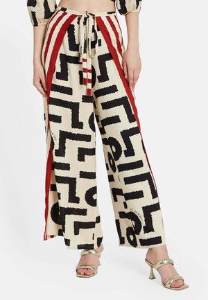 Pantalones de pierna ancha hechos de tejido ligero con una base color crema, patrones geométricos en negro audaces y paneles laterales rojos. Incluye detalle de cintura con lazo.