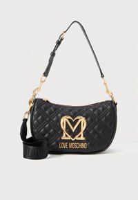 Mala de mão em couro acolchoado preto com ferragens douradas, apresentando um logótipo 'M' proeminente e uma alça destacável com texto em relevo.