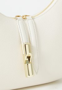 Bolsa de couro texturizado branca com um puxador de zíper em hardware dourado. Apresenta um design elegante e um acabamento suave, destacando os detalhes da costura.