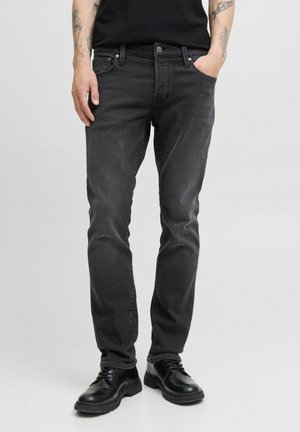 Sorte denim jeans med slim fit, fem-lomme design, let vaskeflair og knaplukning. Båret med sorte lædersko.