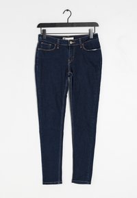 Smala mörkblå jeans i denim, med fem fickor, synlig sömnad i en kontrasterande orange färg och en standard midja.