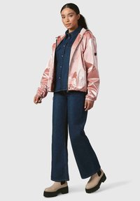 Rózsaszín fémes zipzáros dzseki rugalmas mandzsettákkal, sötét farmeringgel és bővülő kék farmernadrággal párosítva. Bézs platform cipők fekete talppal.