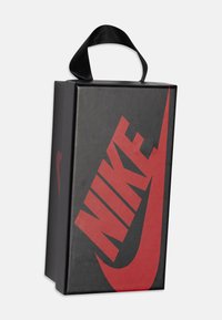 Scatola nera con logo Nike rosso, caratterizzata da una superficie liscia e opaca e una maniglia in tessuto nero sulla parte superiore.