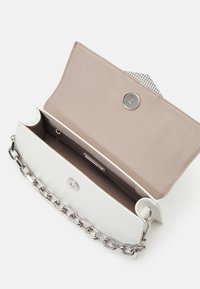 Vit läderhandväska med en silverkedjeaxelrem, ett tryckknappslås och en beige tyginteriör med rutigt mönster.