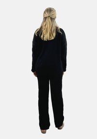 Pull en tricot noir surdimensionné et pantalon assorti en tricot torsadé. Texture douce ; coupe décontractée ; design uni sans motifs visibles.