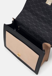 Sac à main rectangulaire noir et beige avec fermoir doré, rabat ouvert révélant la doublure intérieure noire avec motif logo ALDO et poche zippée.