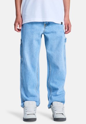 Lichtblauwe denim cargobroek met een losse pasvorm, voorzien van zijzakken en contrasterende stiknaden, gecombineerd met grijze sneakers.