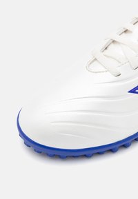 Scarpa da calcio bianca con finitura in pelle liscia, caratterizzata da accenti blu sulla suola e i lacci. Include un design laterale testurizzato e tacchetti sagomati.