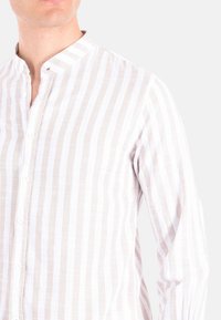 Camicia leggera in lino con strisce verticali bianche e beige alternate, colletto alla cinese e chiusura frontale con bottoni.