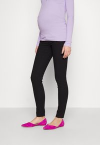 Crne uske hlače u kombinaciji s laganim ljubičastim pletenim topom i zamjenskim ružičastim balerinama; slim fit s glatkom teksturom i minimalnim detaljima.