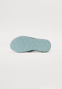Blå gummisåle med et bølgete mønster. Materialet ser holdbart ut, med en glatt tekstur og et sømløst design.