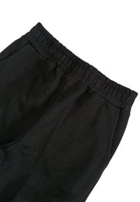 Pantaloni sportivi neri con vita elastica, realizzati in morbido tessuto, dotati di tasche laterali e una texture liscia. Senza motivi né dettagli.