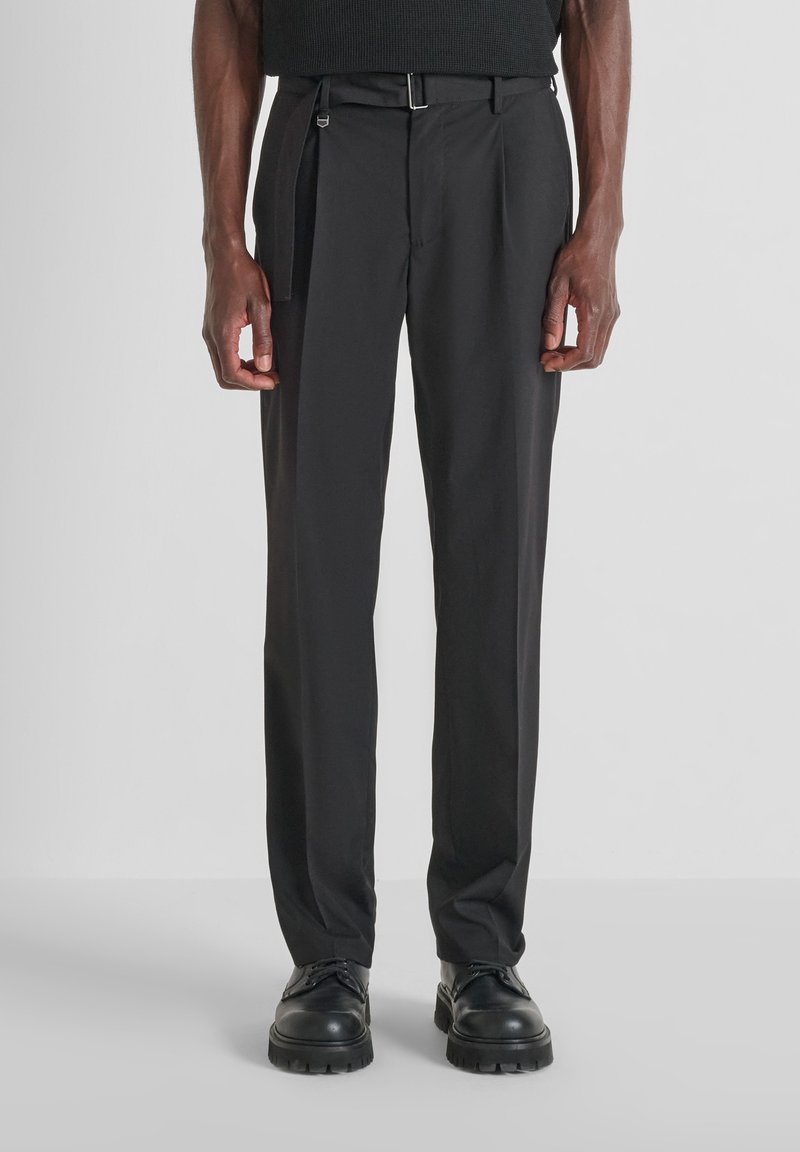 Pantalones negros ajustados con corte recto, hechos de una tela suave, que cuentan con un pliegue frontal, cinturilla y un brillo sutil.