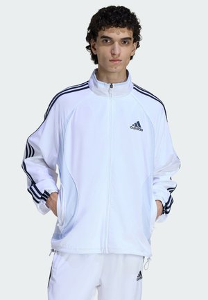 Biała kurtka na zamek wykonana z materiału syntetycznego, z czarnymi paskami Adidas na ramionach i rękawach, z elastycznymi mankietami.