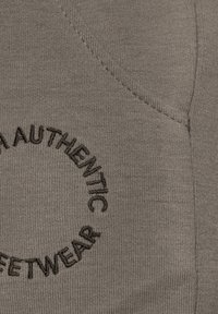Tessuto grigio con un finish testurizzato, con un design ricamato circolare che recita "CALZATURE AUTENTICHE" in evidenza.