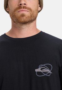 Zwarte t-shirt met korte mouwen van zachte stof, met een klein grijs grafisch logo op de linkerkant van de borst. De halslijn is rond en ontspannen.