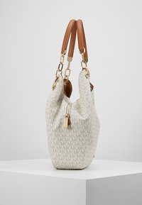 Sac hobo blanc à motif avec un tissu texturé, des poignées en cuir marron, des accents de quincaillerie dorée et une fermeture à glissière.
