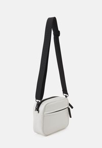 Borsa crossbody bianca con forma rettangolare, tracolla nera regolabile, doppi scomparti con zip e finitura liscia e opaca.