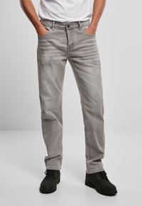 Vaqueros de mezclilla gris claro con corte recto, diseño de cinco bolsillos, sutiles desgastes y detalles envejecidos, combinados con botines negros.