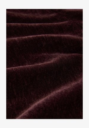Bordeauxfarbener Stoff mit einer weichen, strukturierten Oberfläche, sanften Falten und subtilen Schattierungsvariationen, nah aufgenommen.
