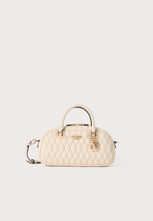 Sac à main matelassé crème avec double poignée, ferrures dorées, charme logo et bandoulière amovible sur fond clair uni.