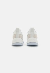 Baskets blanches et gris clair avec une finition en cuir lisse, des accents en daim, des tirettes et une semelle en caoutchouc bleu clair.