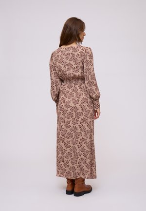 Maxi dress in a soft fabric with a pink base, featuring a floral pattern in maroon, long sleeves, and a fitted waist. Brown ankle boots.