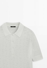 Biała koszulka polo z krótkim rękawem wykonana z teksturowanej dzianiny z małymi kwadratowymi otworami oraz plisą zapinaną na guziki.