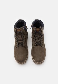 Bottes mi-hautes en daim marron avec doublure en tissu foncé, matériel métallique et design à lacets. Présentent des accents cousus le long de la semelle.