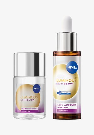Duo Nivea Luminous Skin Glow: una bottiglia di vetro chiaro con un tappo argento (lozione) e una bottiglia di vetro marrone con pipetta (siero), caratterizzate da accenti blu e oro.