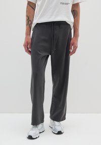 Graue Sweatpants mit einem elastischen Bund und Kordelzugdetails. Der Stoff wirkt weich und leicht strukturiert und bietet einen lässigen Schnitt.