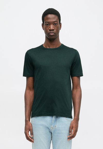 Τίγκα καφέ μπλούζα με κοντό μανίκι και στρογγυλή λαιμόκοψη, φτιαγμένη από λείο ύφασμα, συνδυασμένη με ανοιχτό μπλε τζιν παντελόνι. Απλός σχεδιασμός χωρίς σχέδια ή διακοσμητικά.